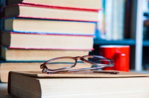 Closeup of reading glasses on the book, pile of books